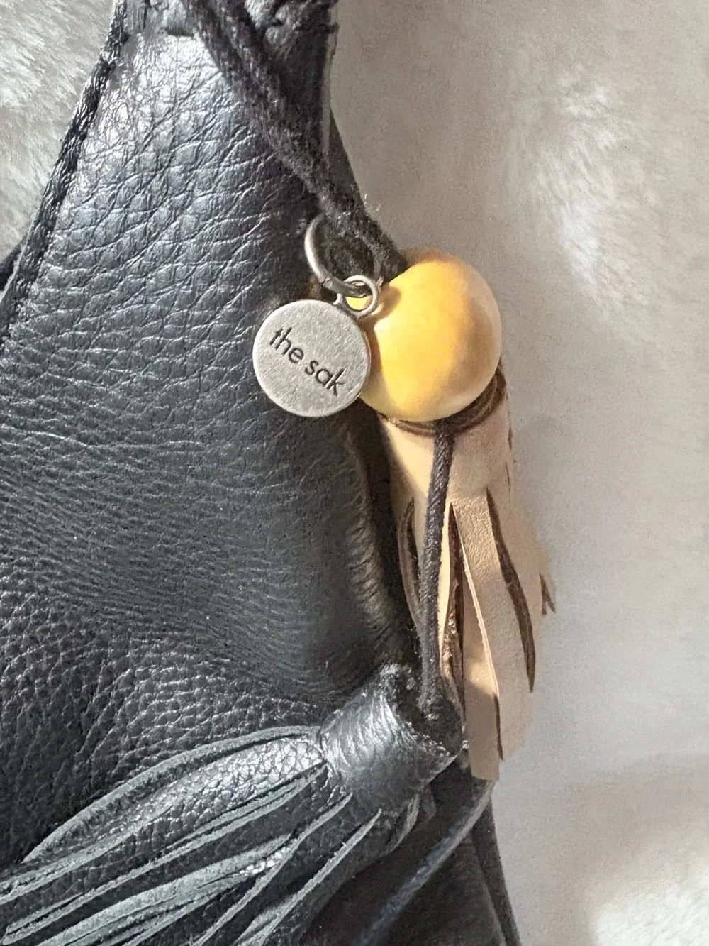 The Sak Black Leather Shoulder Bag with Tan Tassel Charm